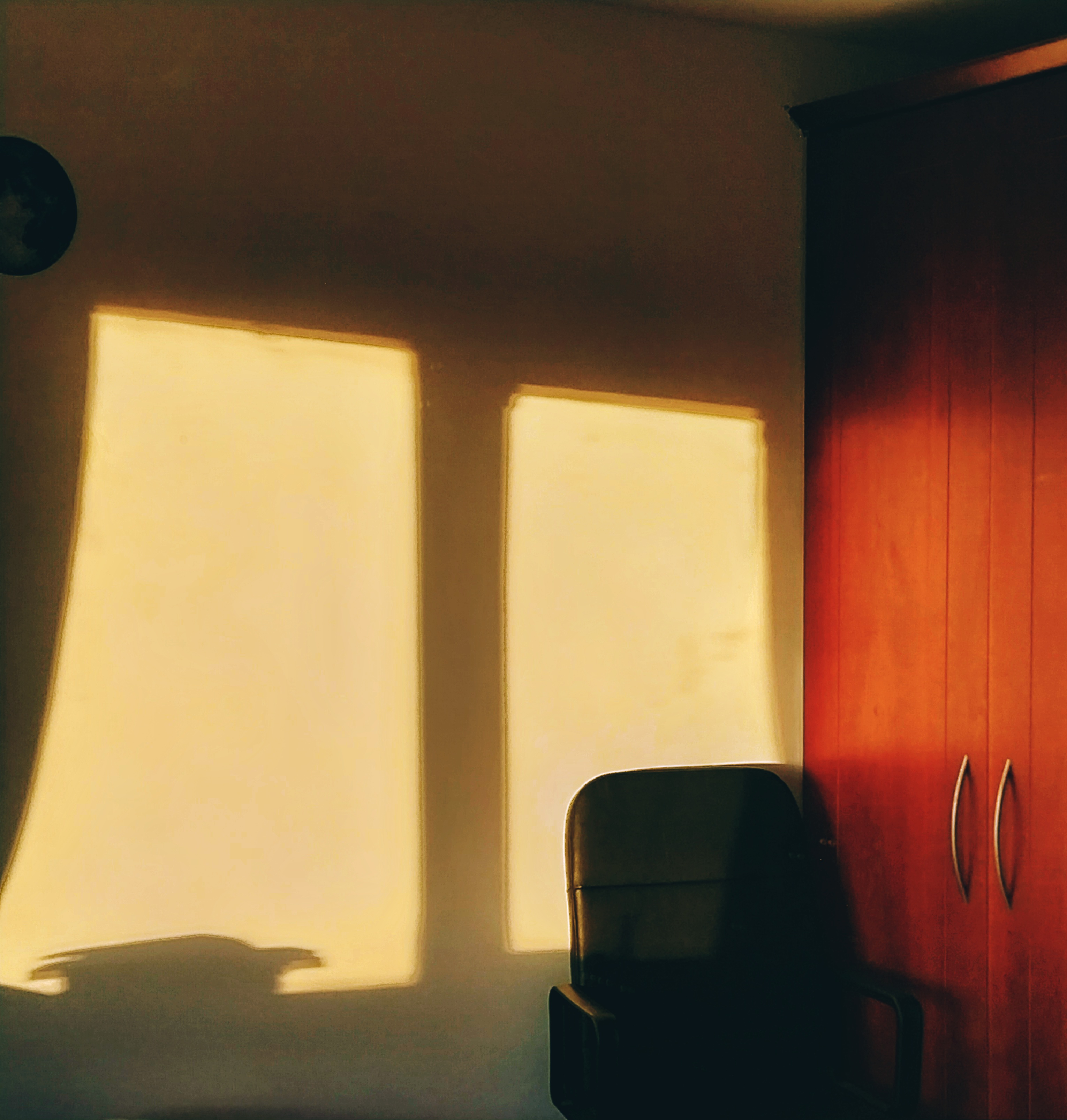 An alternate angle of a high contrast scene with a chair in the sunrise.